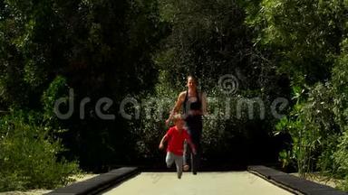 有趣的小男孩和妈妈一起在公园的蹦床跑道上奔跑和跳跃。
